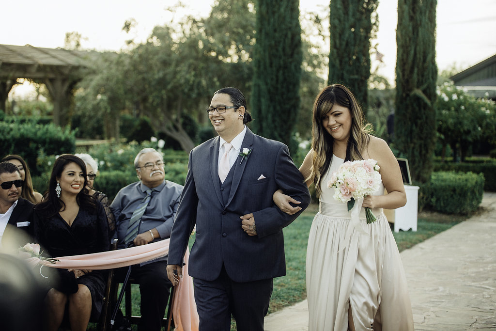 Wedding Photograph Of Groomsman And Bridesmaid Smiling While Passing The Aisle Los Angeles