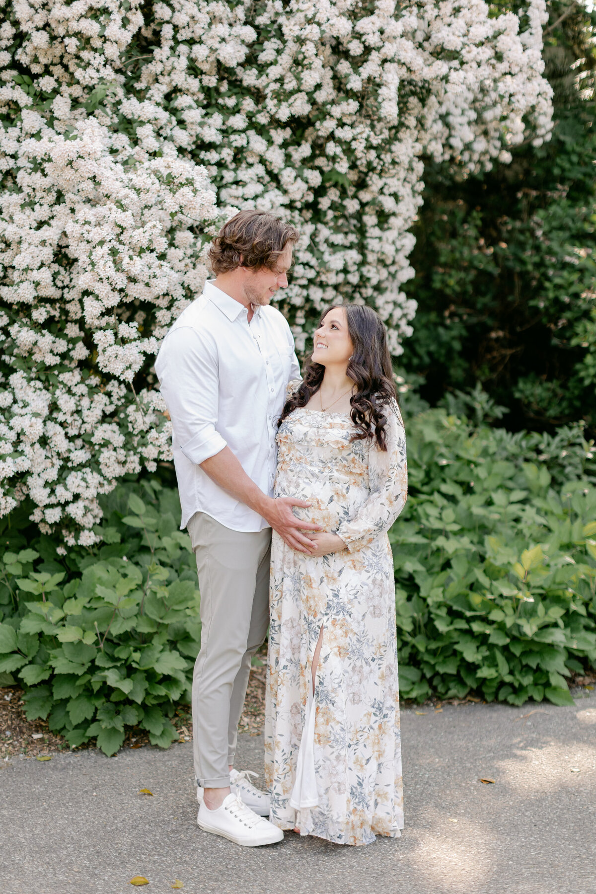 pregnant couple in front of blooming flowers by Philadelphia Maternity Photographer