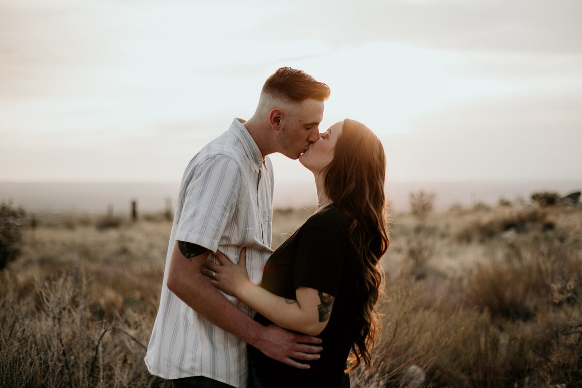 engaged couple kissing in the desert