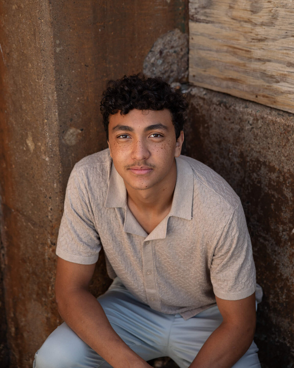 Senior boy sitting in the corner of an industrial building.