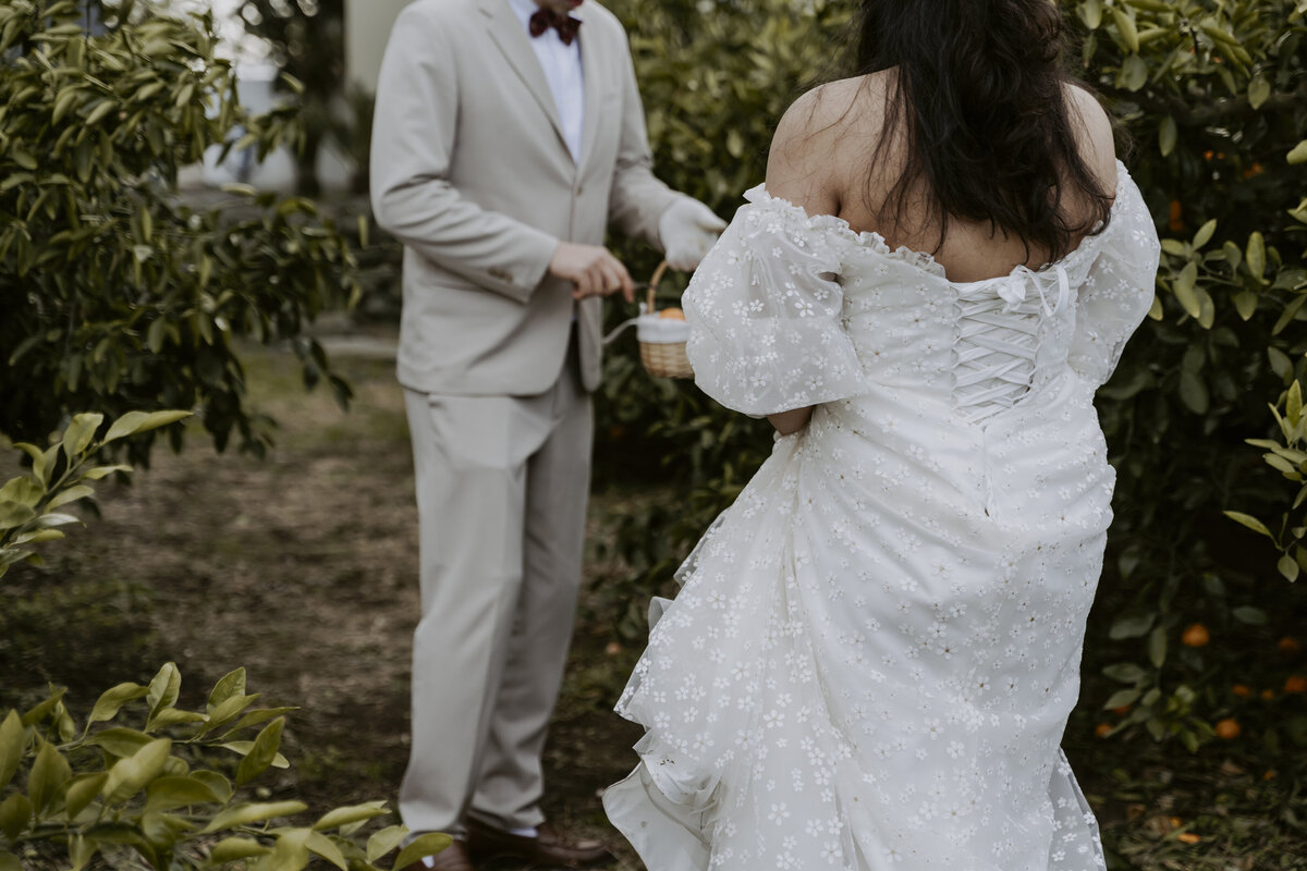 the bride wearing an off shoulder white dress while the groom wears a gray suit and black bow tie