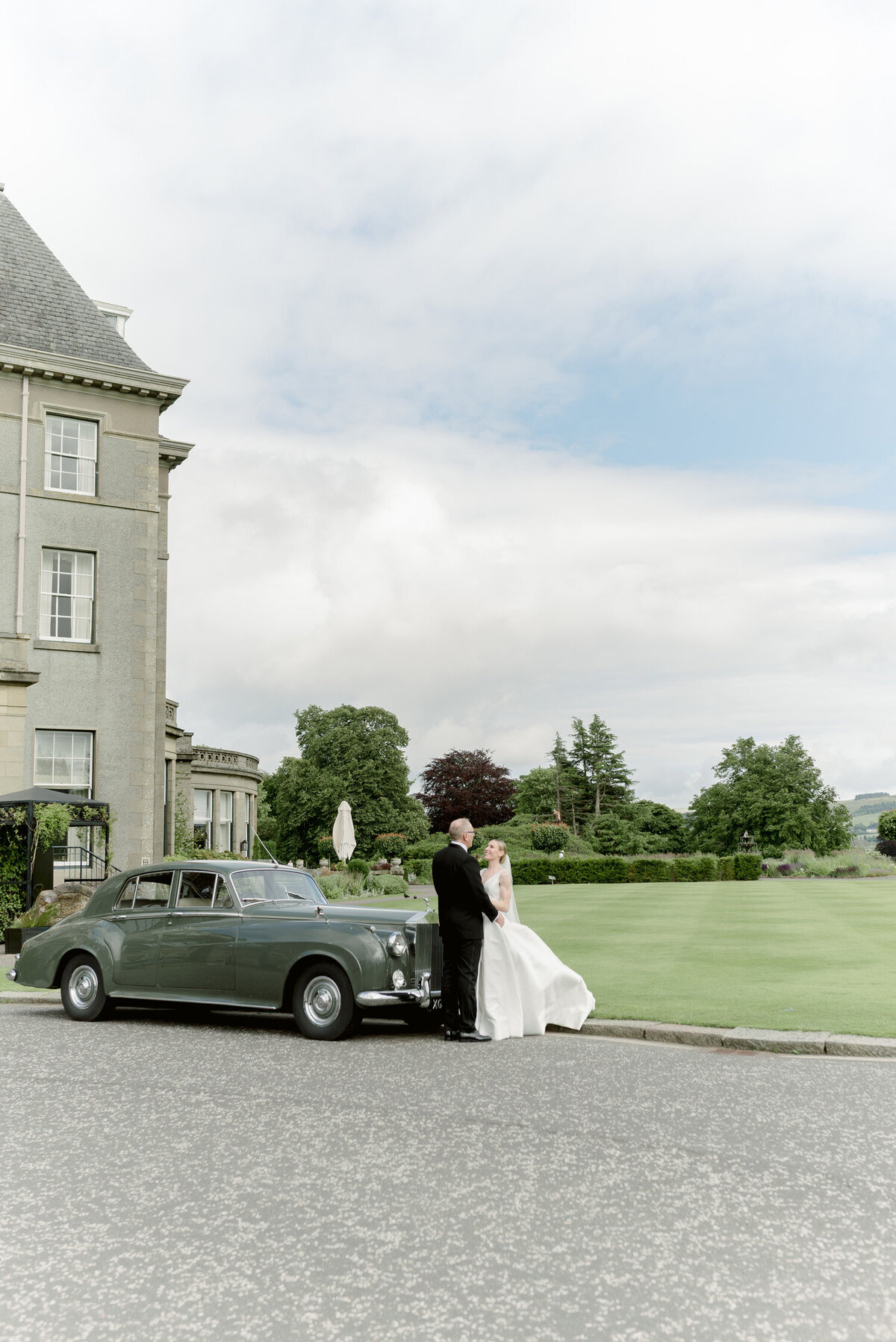 Bride and Groom at the front of the hotel on their Gleneagles wedding day. Image by luxury wedding photographer uk, Jill Cherry Porter.
