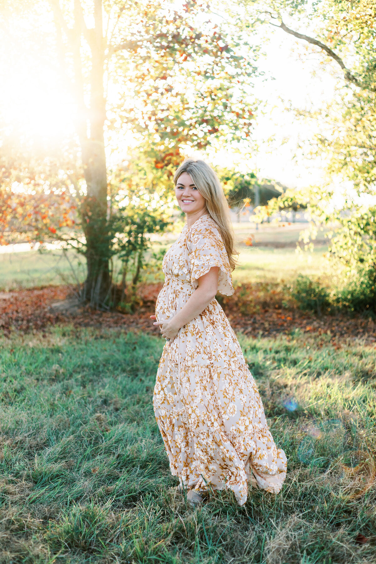 pregnant mom in field with sunset light behind her