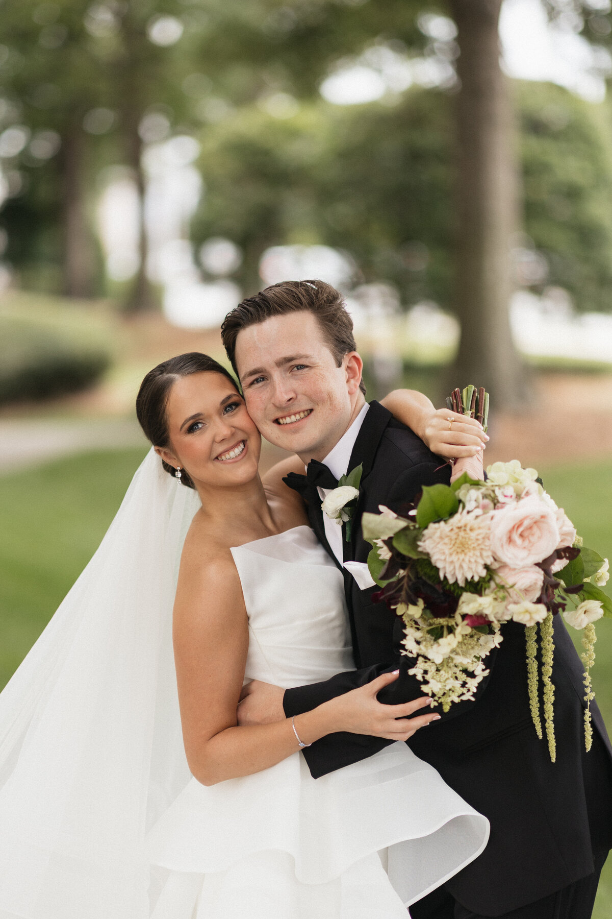 Bride and groom smiling into the camera beautifully on their wedding day.