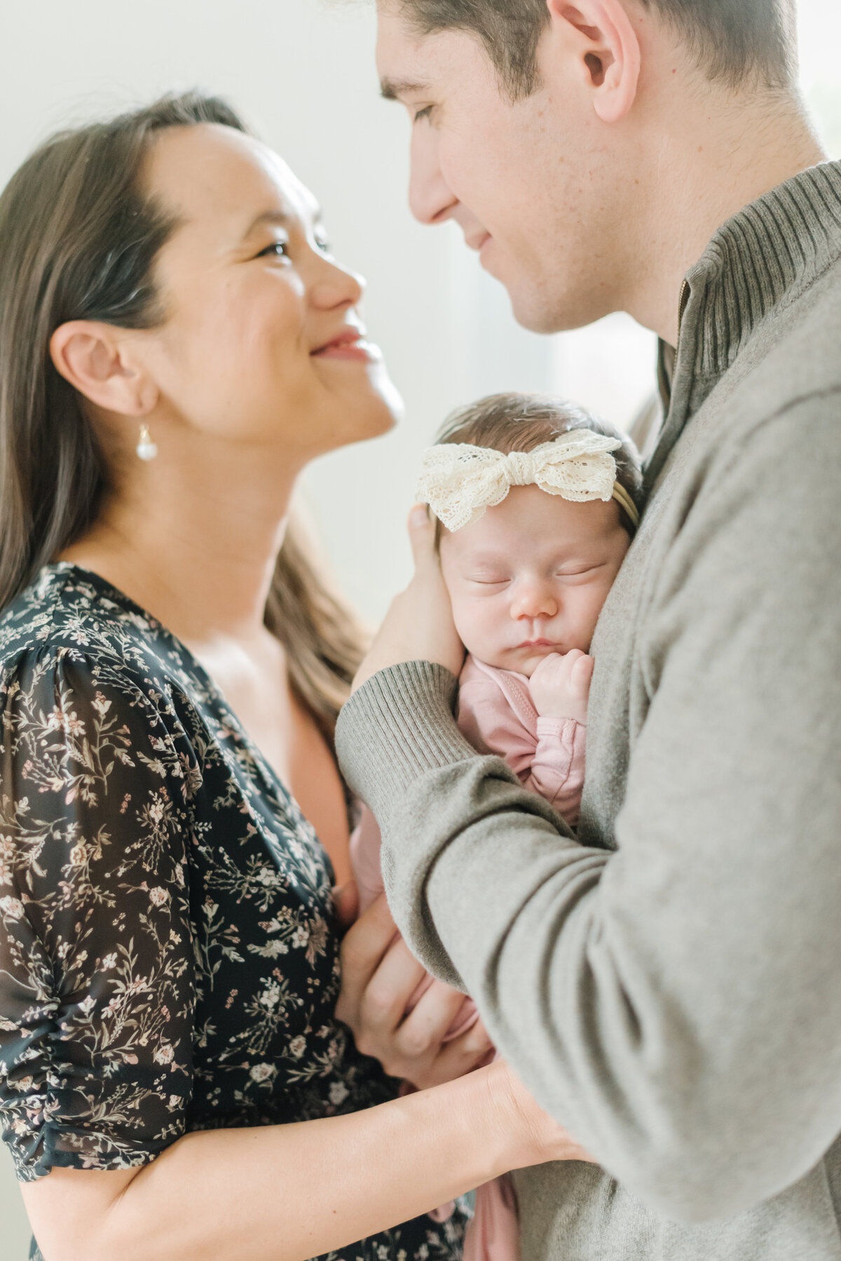 Mom and dad looking at each other while holding newborn - Northern Virginia Newborn Photographer