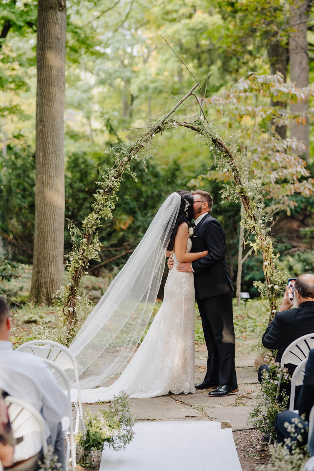 Bride and groom kissing after marriage ceremony in a forest, Finger Lakes, NY