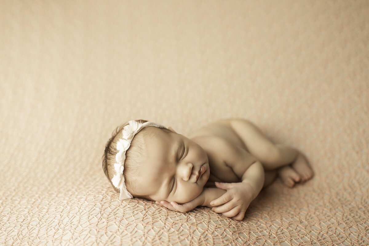 Newborn baby girl peacefully sleeping, her tiny hands resting gently as she lays in a soft and cozy setup, creating a timeless and delicate portrait