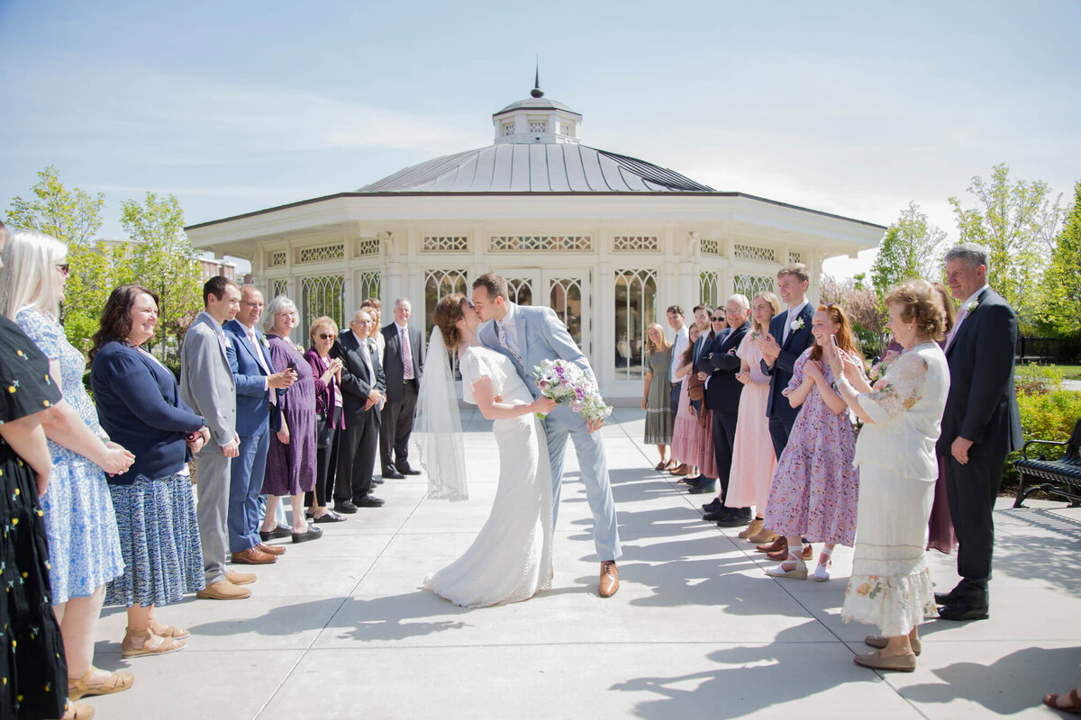 a bride and groom kissing with people lined up around them