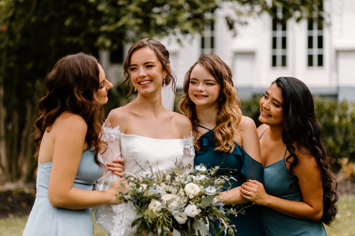 bride and her bridesmaids smiling at each other
