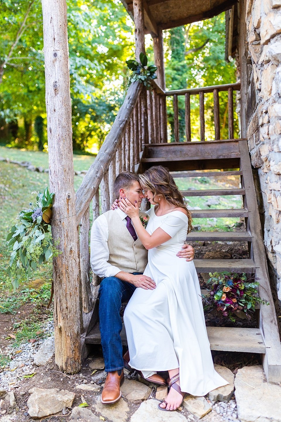 Bride and groom seated on staircase sharing a moment in rustic Asheville wedding.