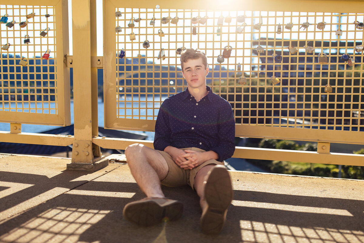 Your senior photos Pittsburgh boy posing on Roberto Clemente Bridge during Sunset.