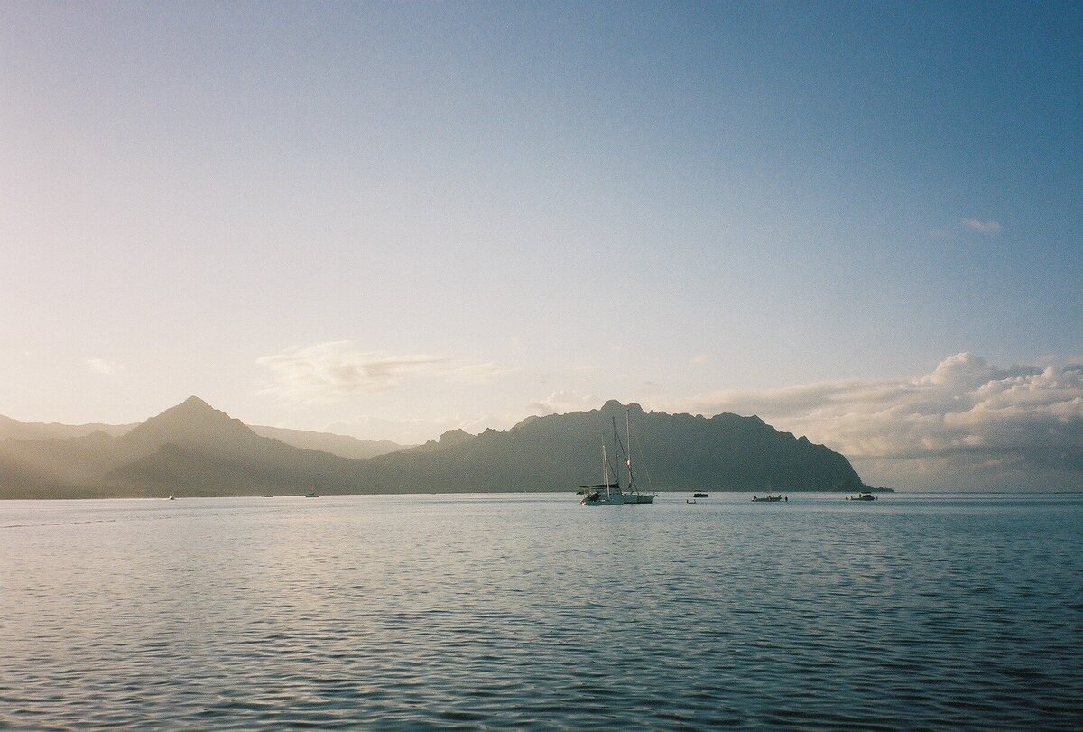 Sunrise with soft light illuminating mountains and the sea, captured on film by Kate Winters Photography, showcasing the tranquil beauty of the natural landscape in an authentic, documentary style.