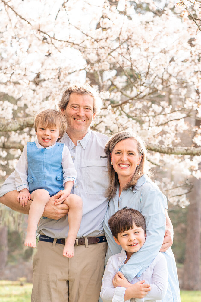 Lookout Mountain photographer Kelley Hoagland takes joyful, bright family photos of family posing in front of Cherry Blossoms.