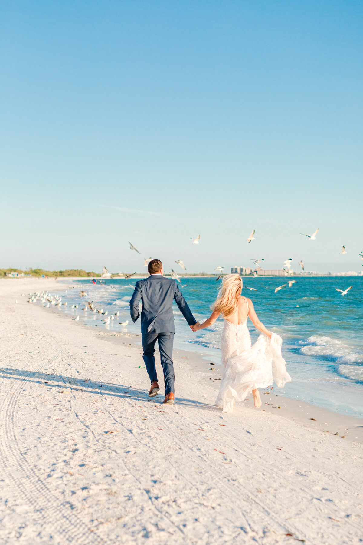 bride and groom running along the beach taken by wedding photographers sarasota