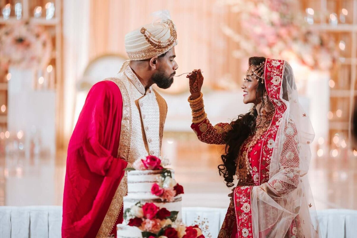 Bride and groom during cake cutting feeding each other cake.