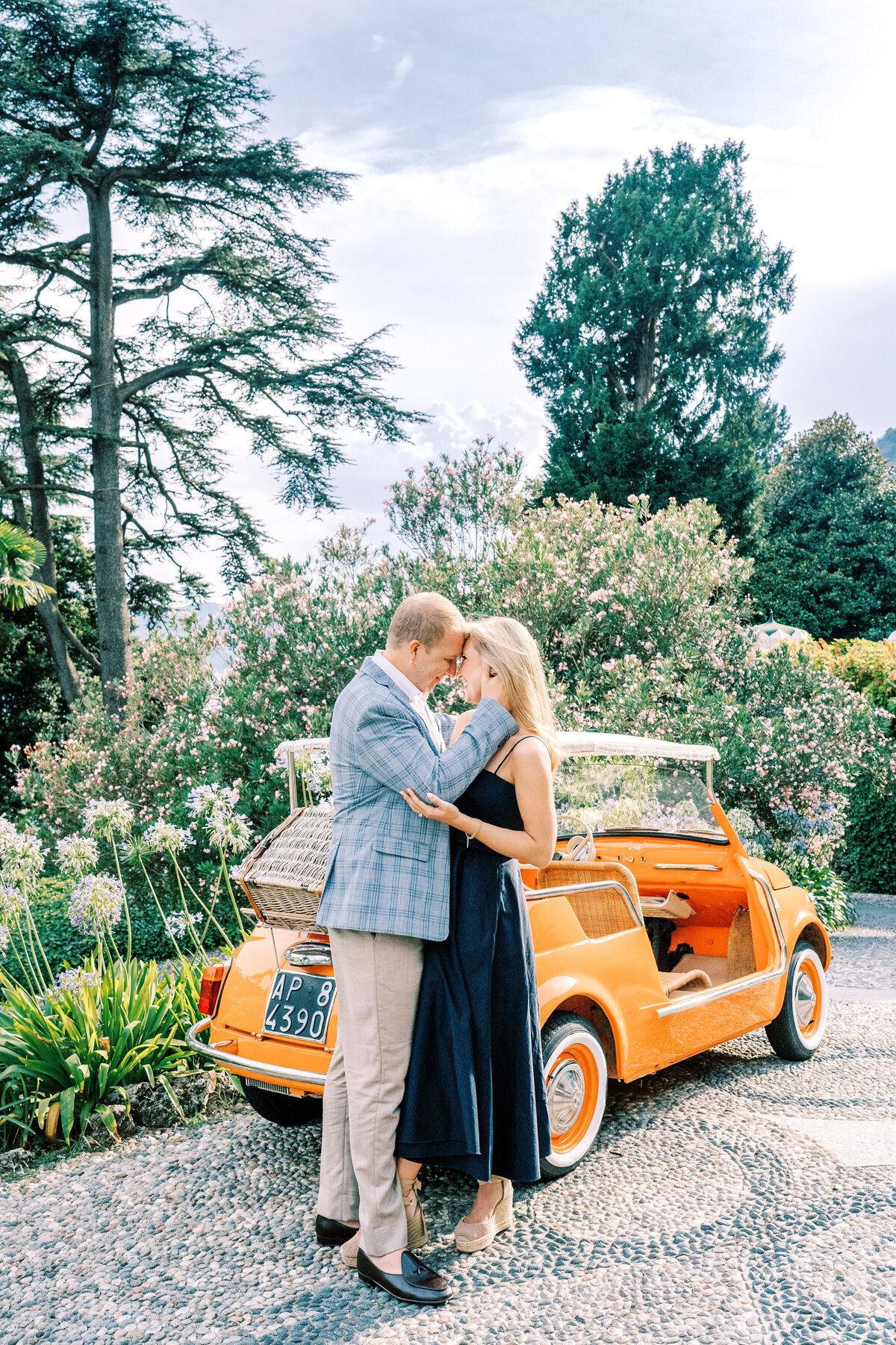 Film photograph of couple next to vintage orange car at their  engagement session at Passalacqua on Lake Como Italy
