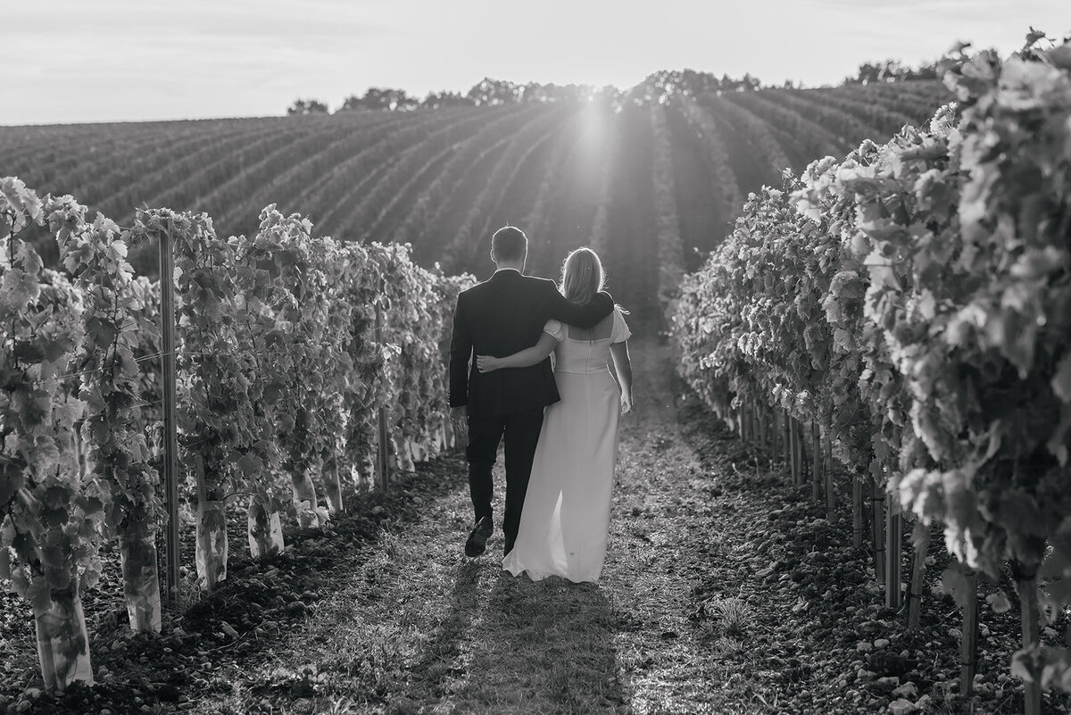 Bride and Groom walking through the french vineyards with their arms around eachother