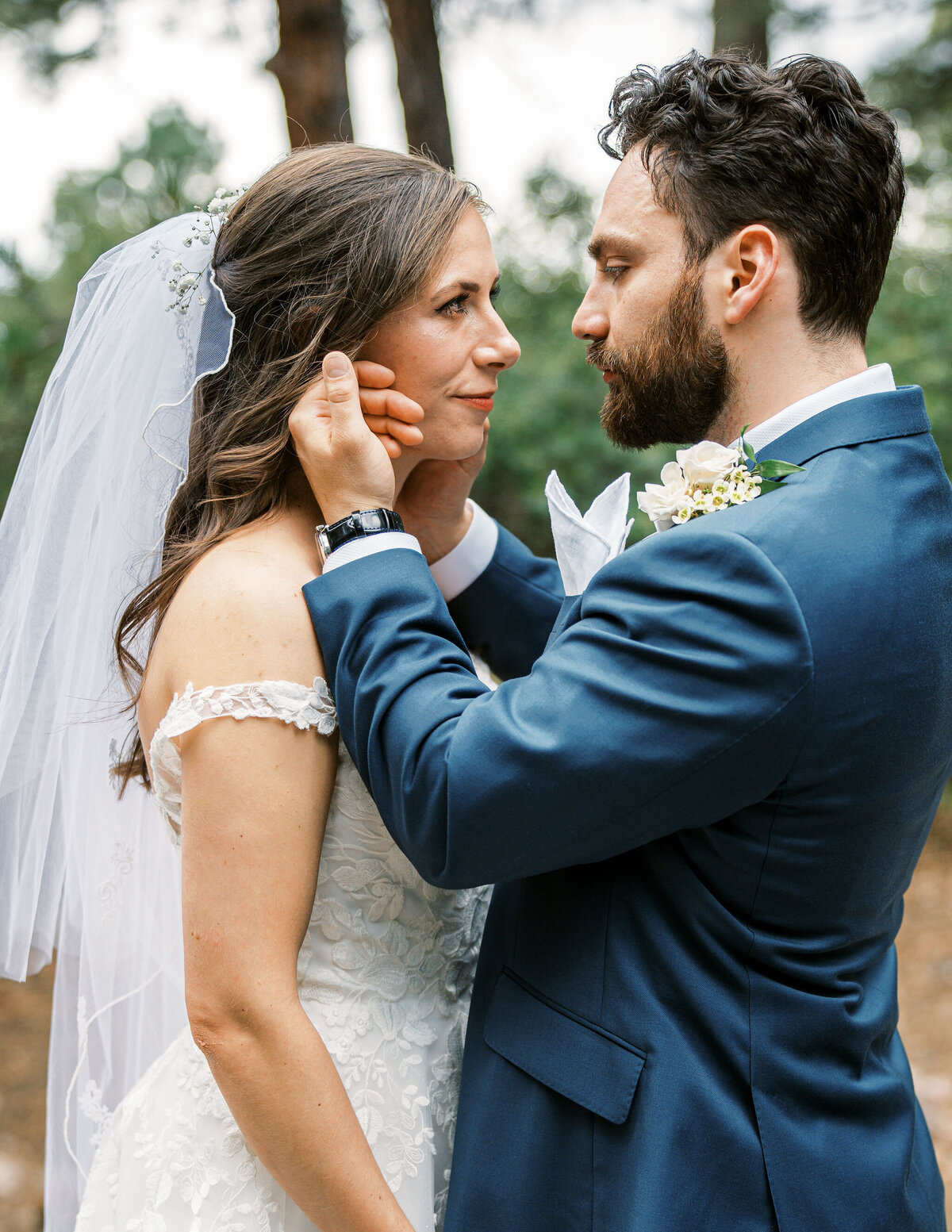 groom embraces bride and rubs her cheek