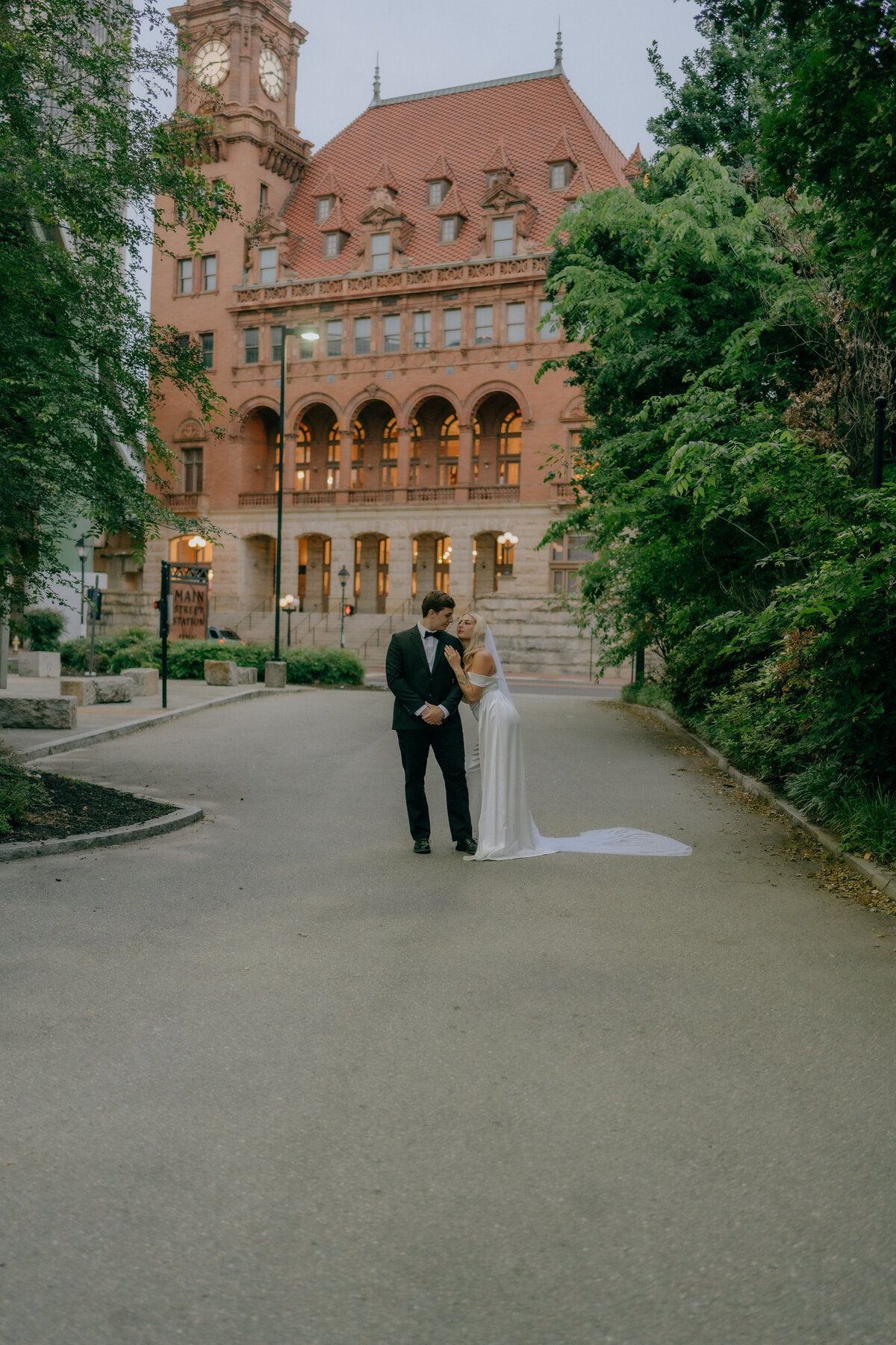 A newlywed couple embraces lovingly on the street in front of the historic Main Street Station in Richmond, Virginia, capturing an intimate elopement moment by Quinn Photography LLC.