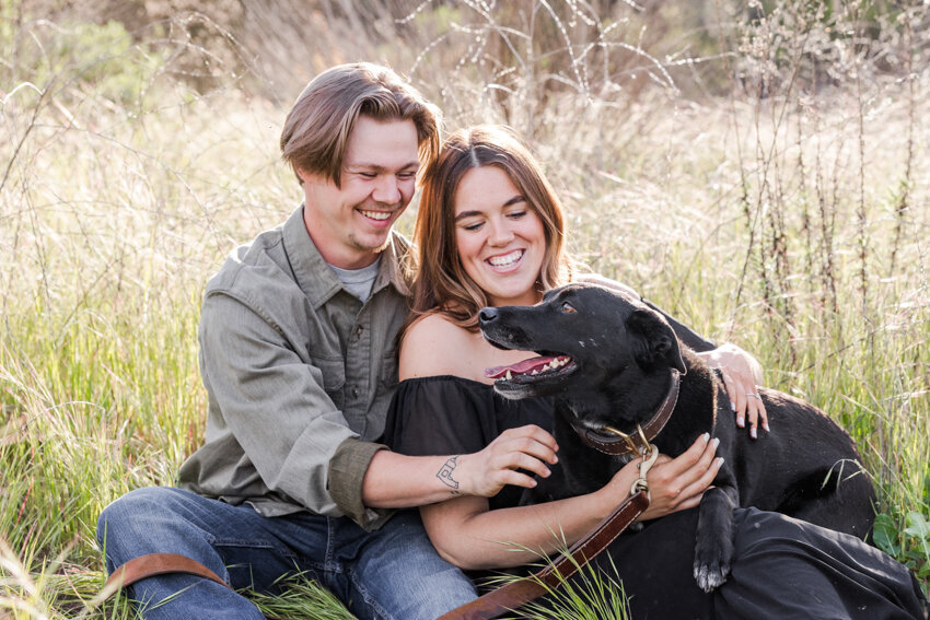 engaged-couple-hugging-dog-in-field