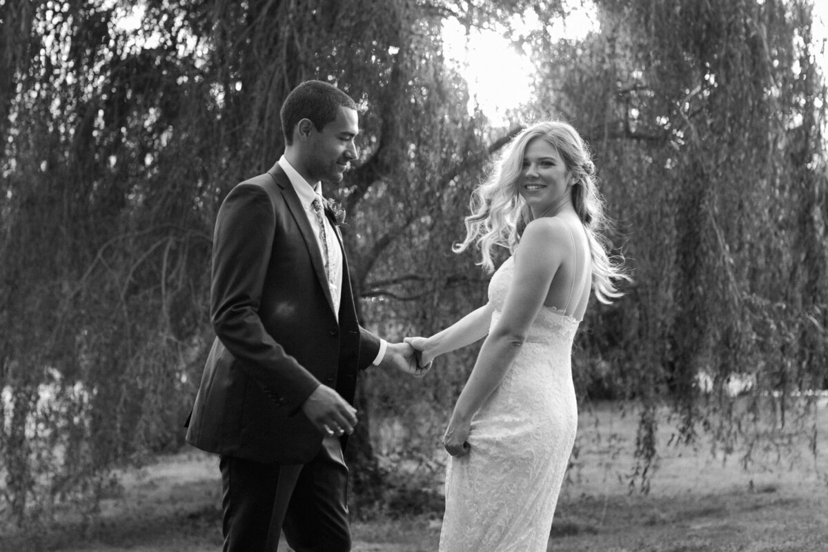 Black-and-white-photo-of-bride-and-groom-dancing-at-golden-hour-on-wedding-day-in-front-of-trees-at-venue-Twin-Willow-Gardens-in-Snohomish-WA-photo-by-Joanna-Monger-Photography