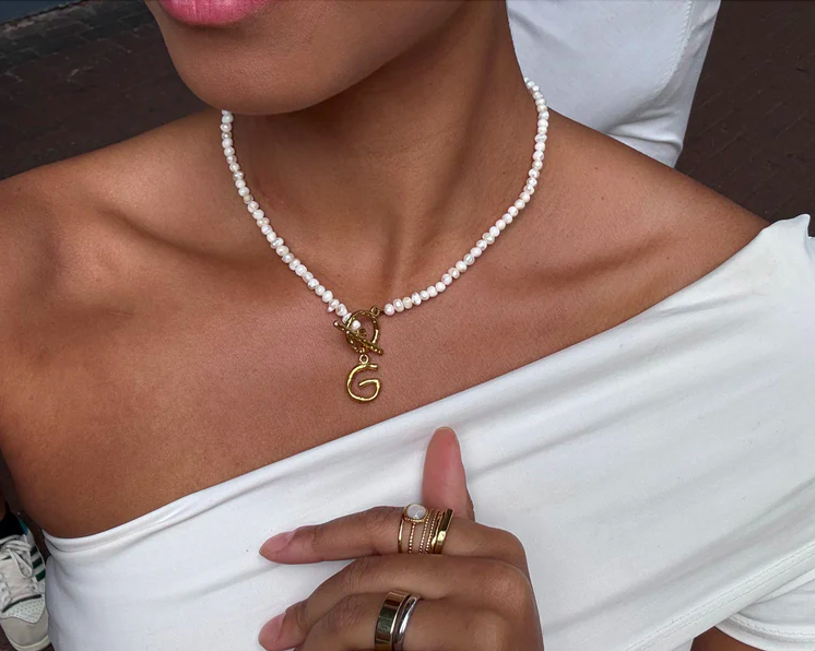 Image shows a hand  in a clinical black glove holding a dermaplaning scalpel against a white wall