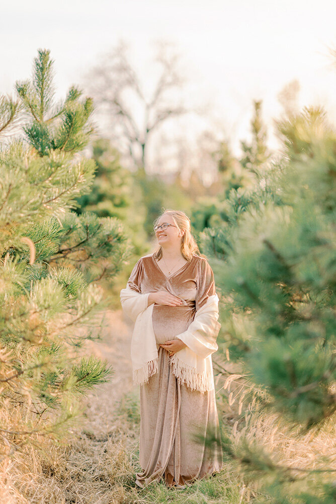 Pregnant woman wearing a pink dress and white shawl for her winter maternity photos
