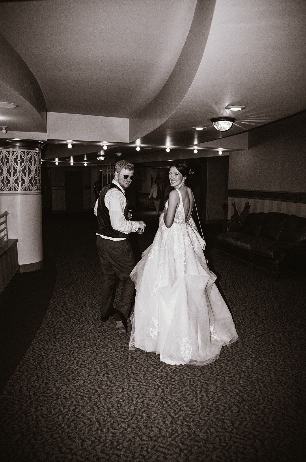 high flash editorial black and white photo of bride and groom walking away 