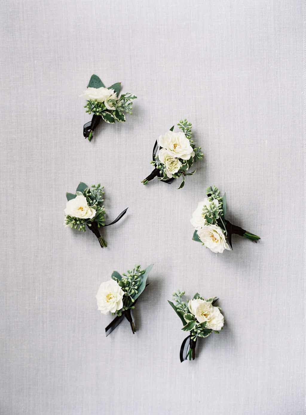 boutonnieres of white roses, babys breath, and black ribbon