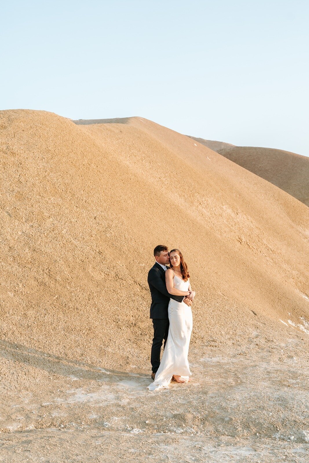 A bride and groom standing on Maslin Cliffs getting married