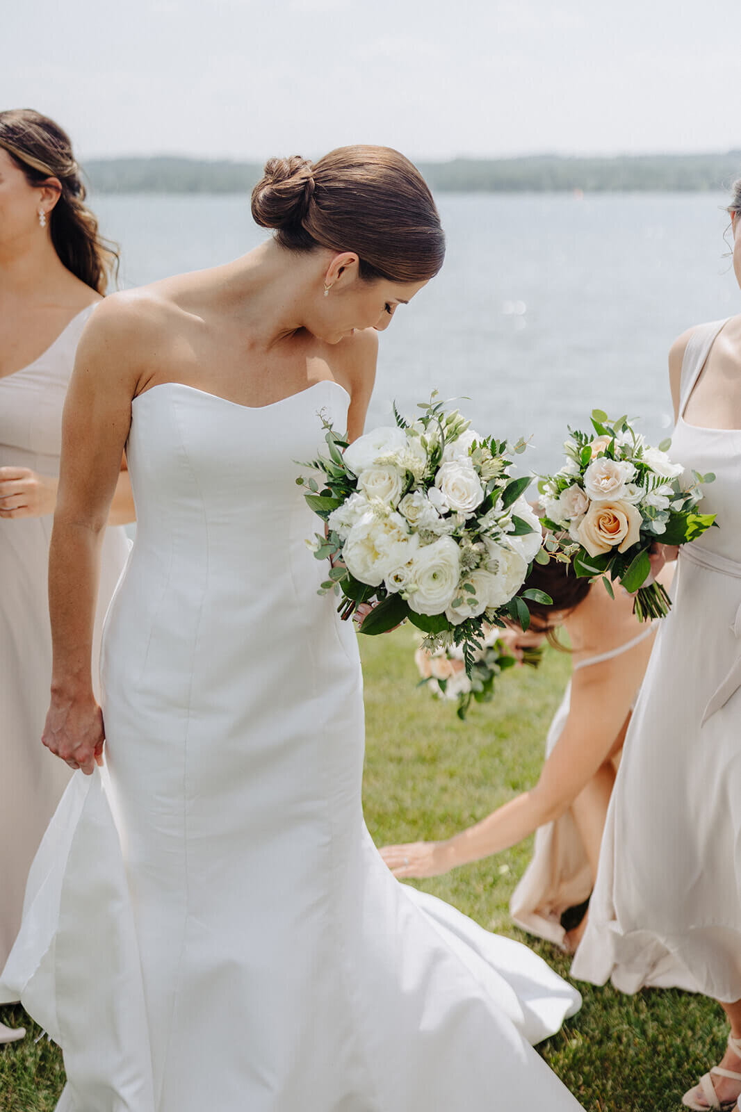 Bride having dress fixed by bridesmaid