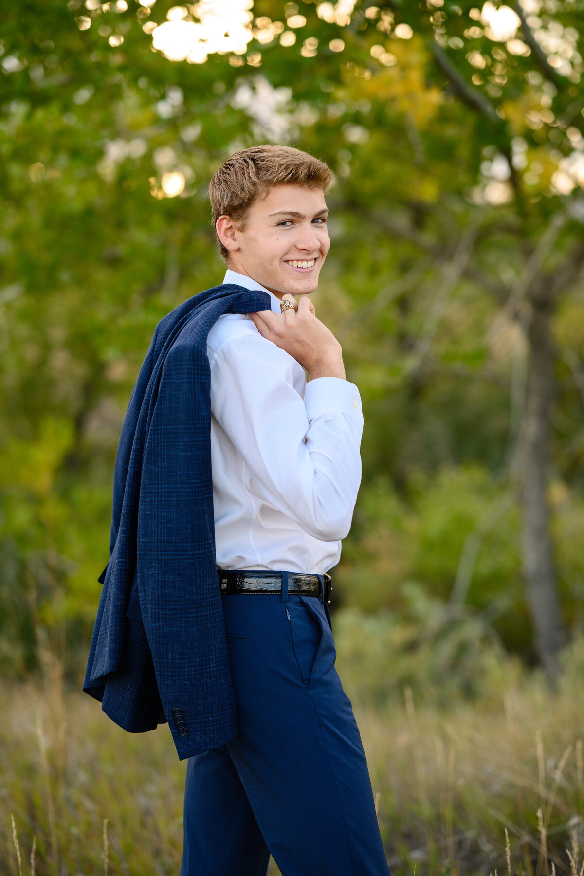 senior photo ideas for guys with a young man in a suit with the jacket slung over his shoulder