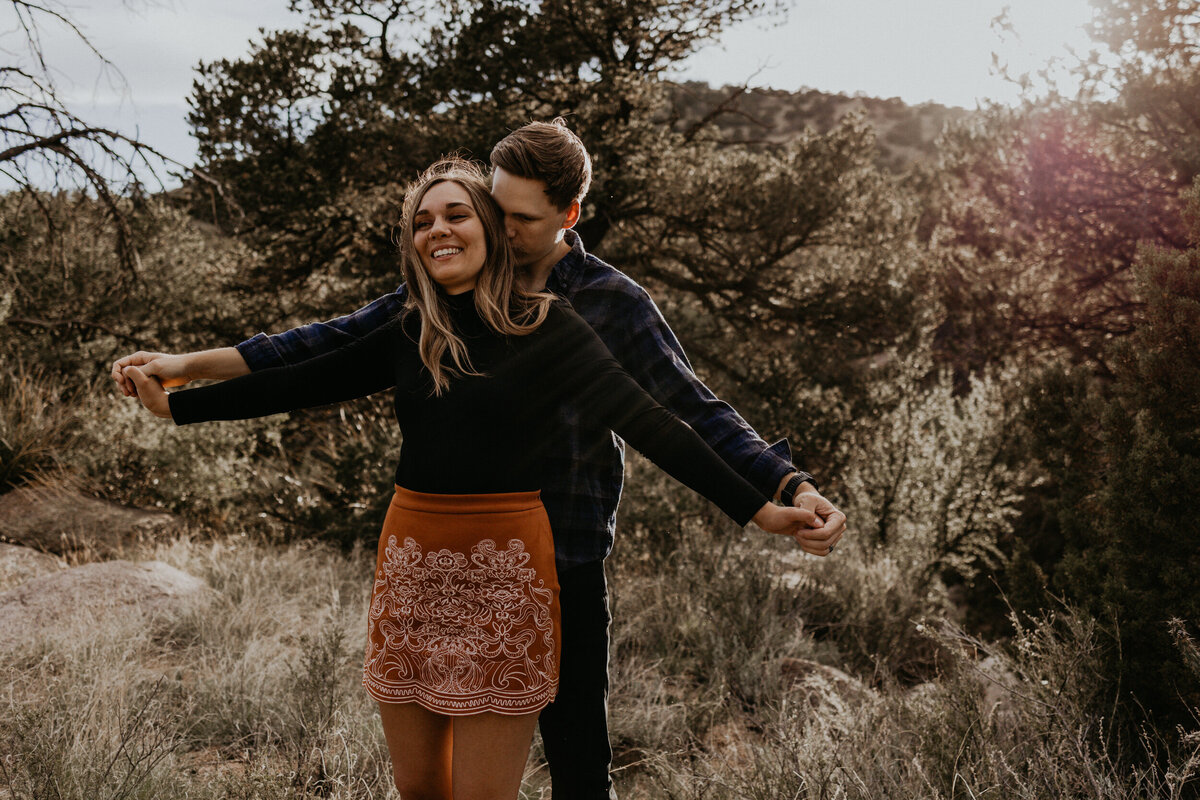 engaged couple walking through the desert laughing and holding hands