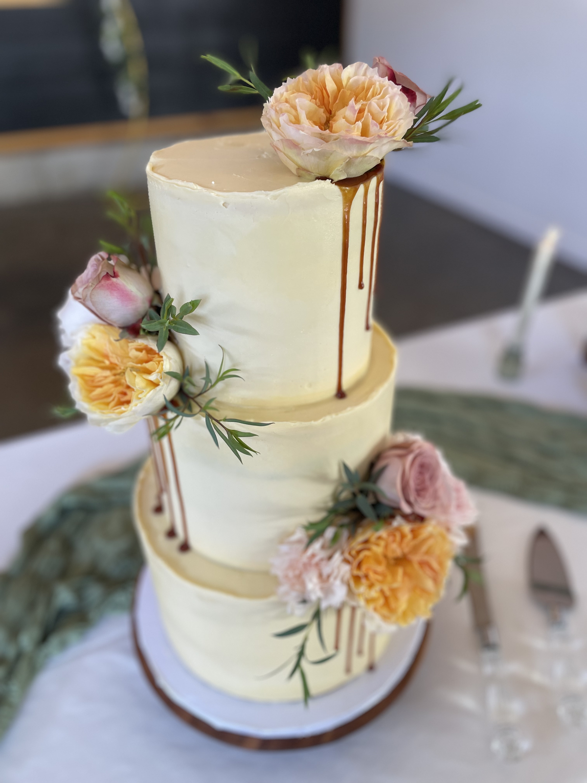 Gluten-free wedding cake with caramel drip and peach florals, designed by Grain Artisan Bakery in Snohomish to blend modern style with handcrafted artistry.