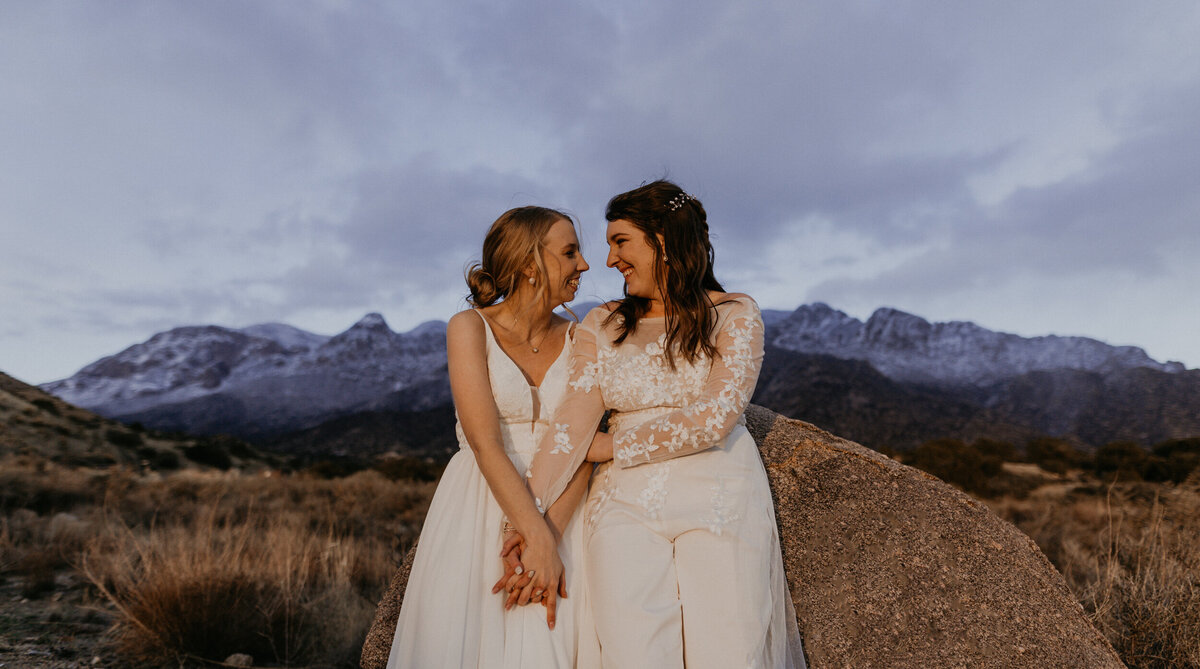 newlywed LGBTQ+ couple holding each other in front of the Sandia mountains in Albuquerque, New Mexico