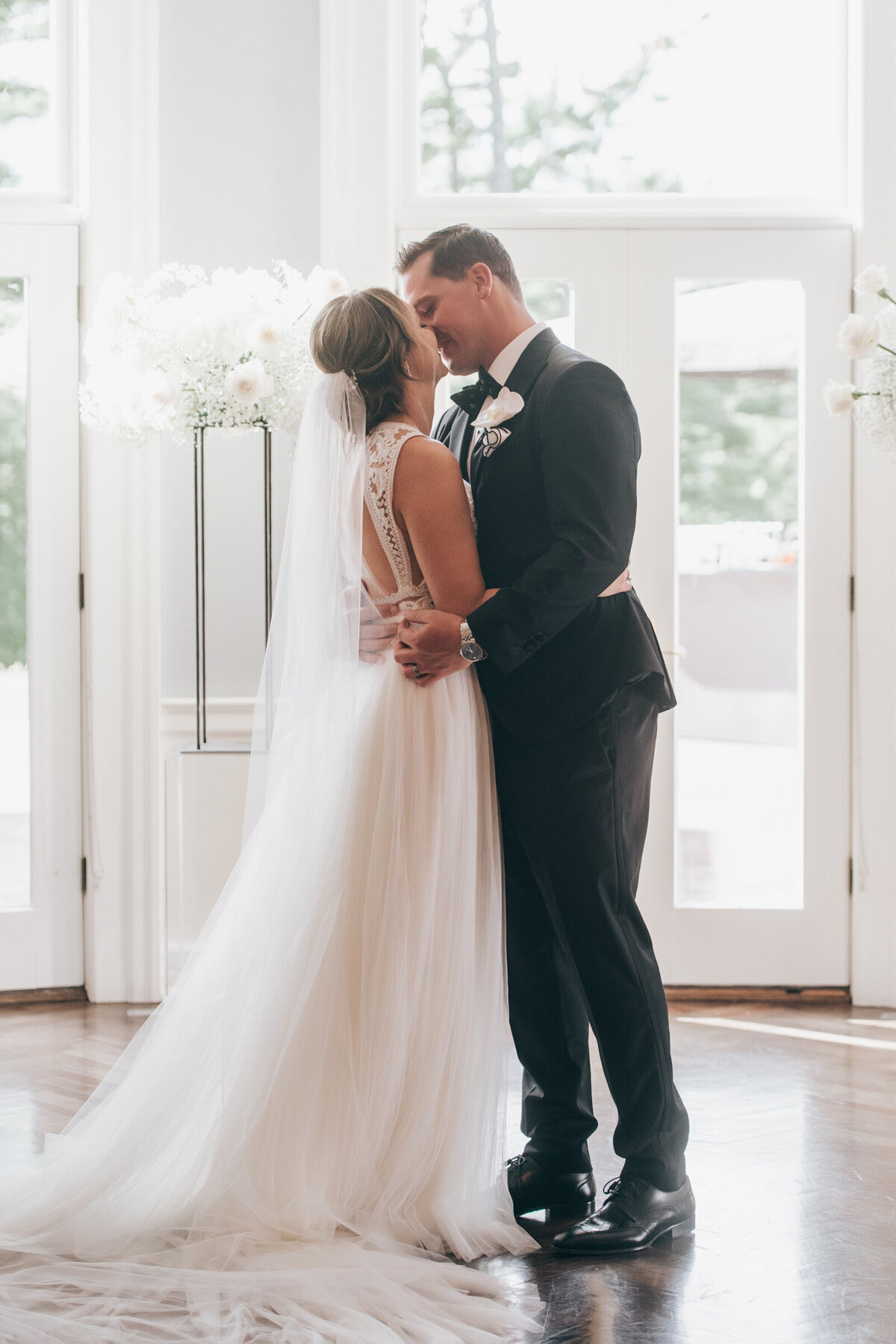 Bride and groom first kiss during their indoor wedding ceremony at the London Hunt Club