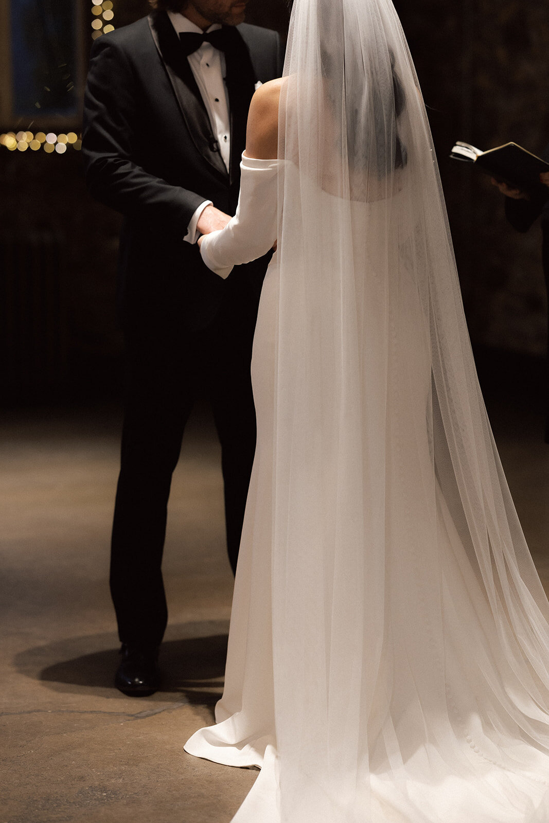 Cinematic wedding photo of bride and groom exchanging vows, highlighting the elegant bridal veil and authentic emotion of the ceremony.