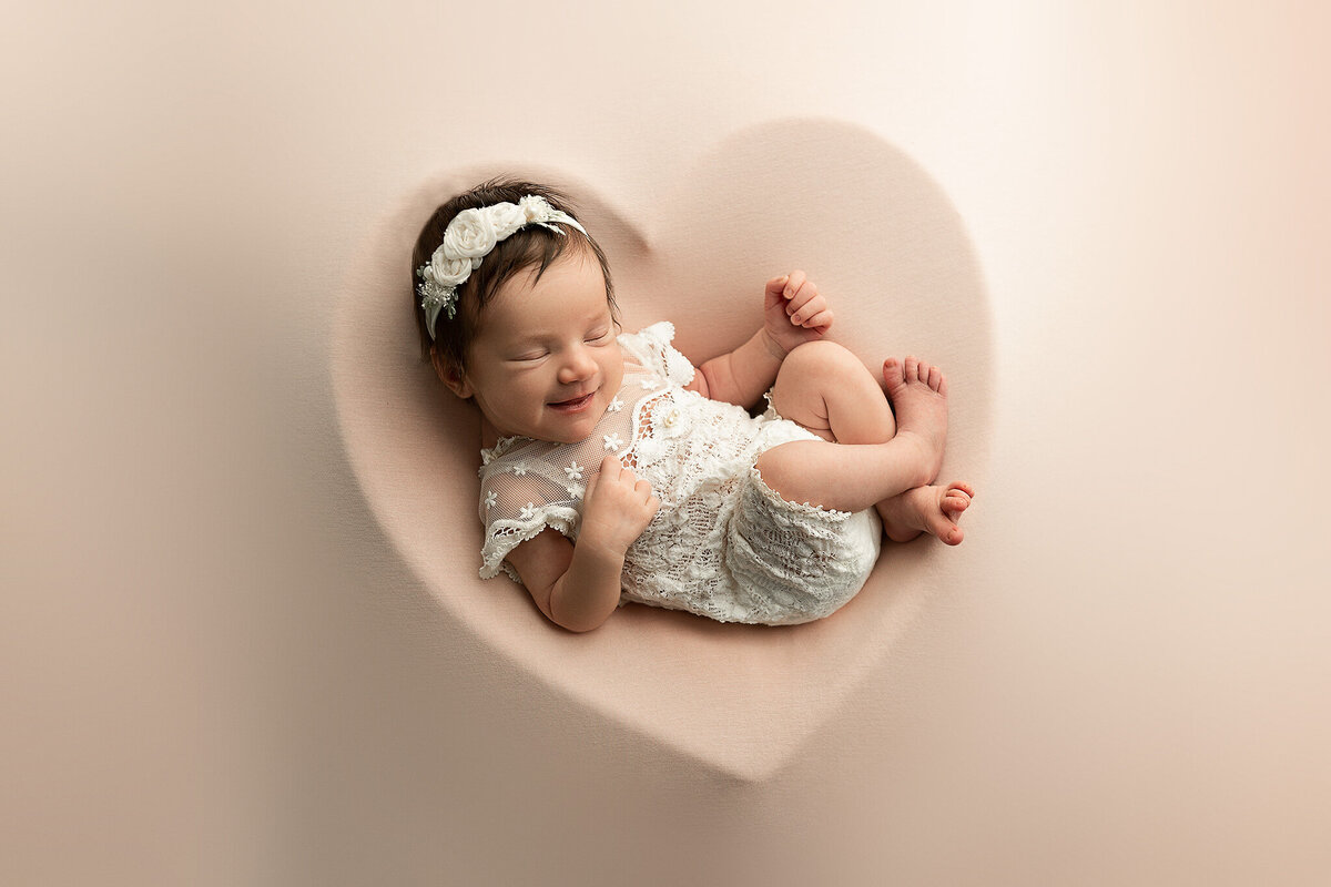 dayton-and-columbus-ohio-newborn-photographer-baby-girl-in-white-lace-romper-within-heart-shape-on-blush-pink-blanket-amanda-estep-photography