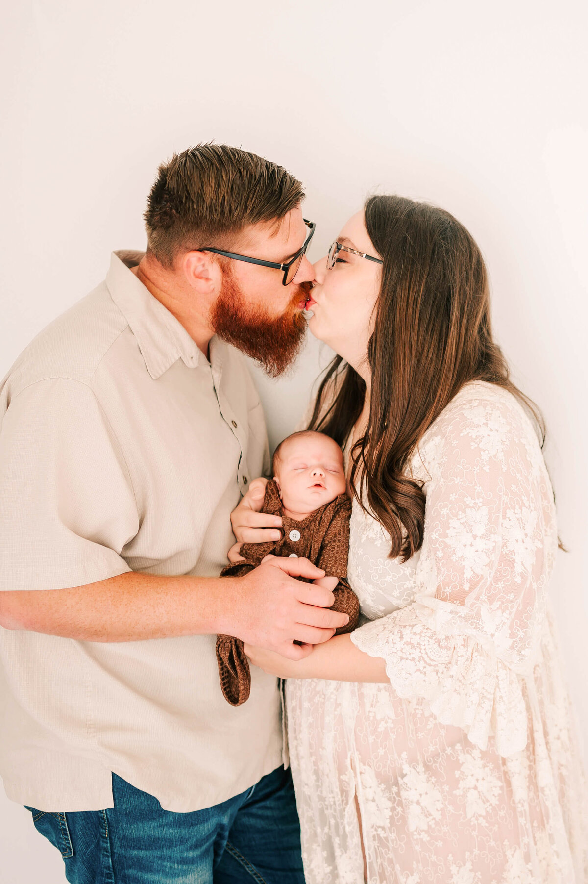 parents kissing holding newborn in Springfield MO newborn photography