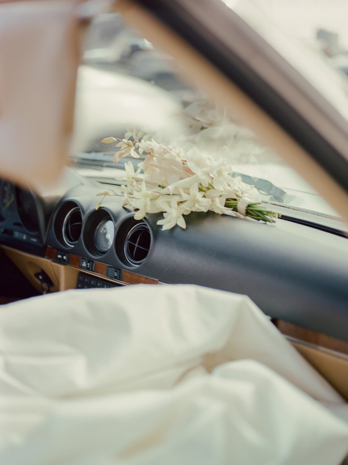 soft orchid wedding bouquet resting on dash of vintage mercedes convertible in Detroit, Michigan