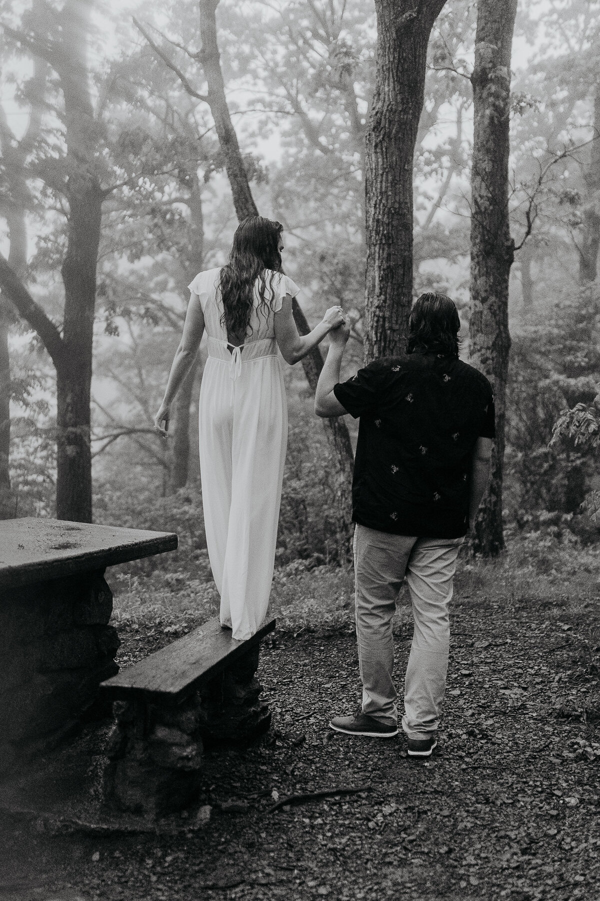 couple walks through forest on bench