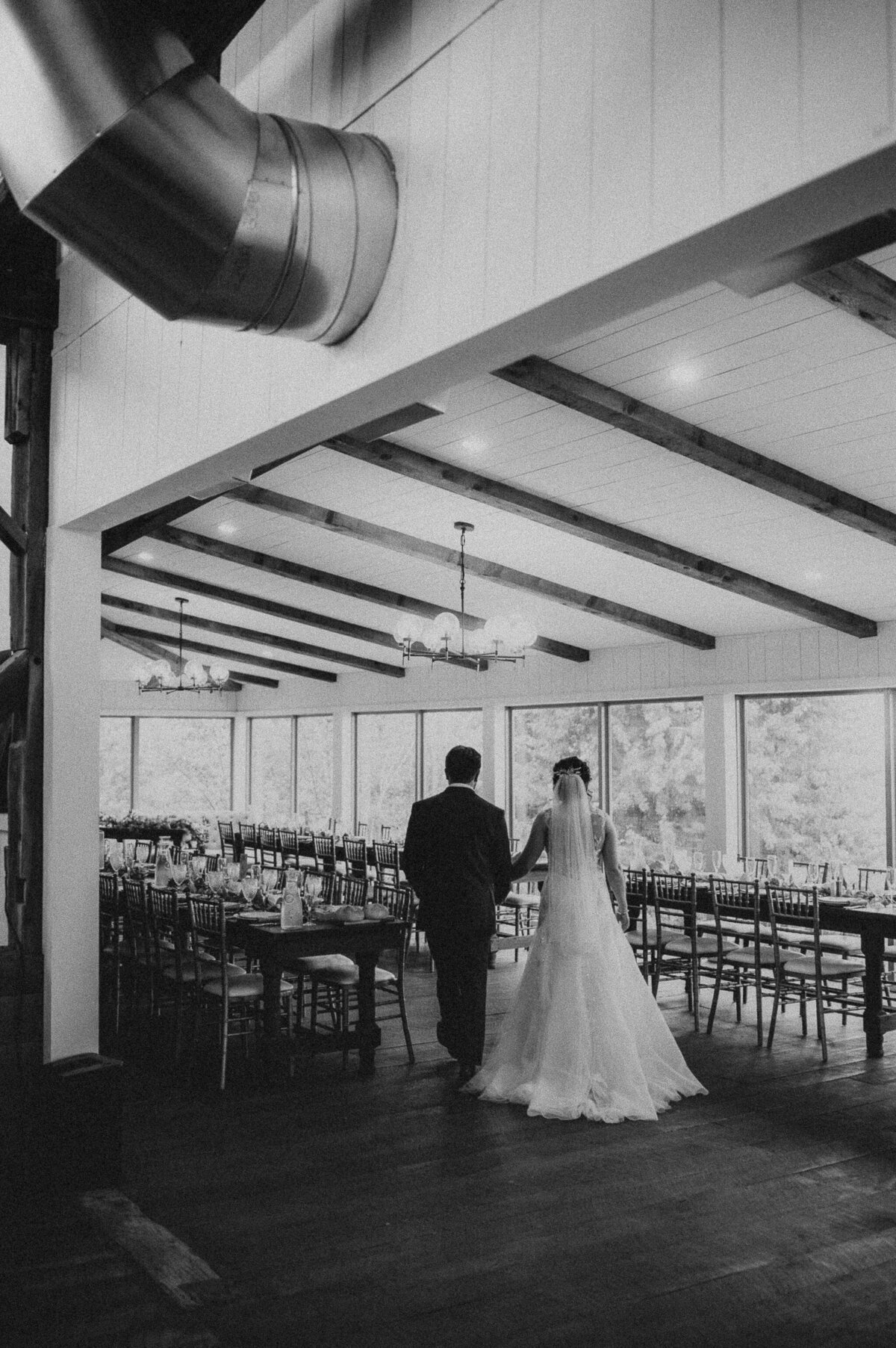 a black and white image of a bride and groom walking through the reception space alone at the Willowbrook wedding venue