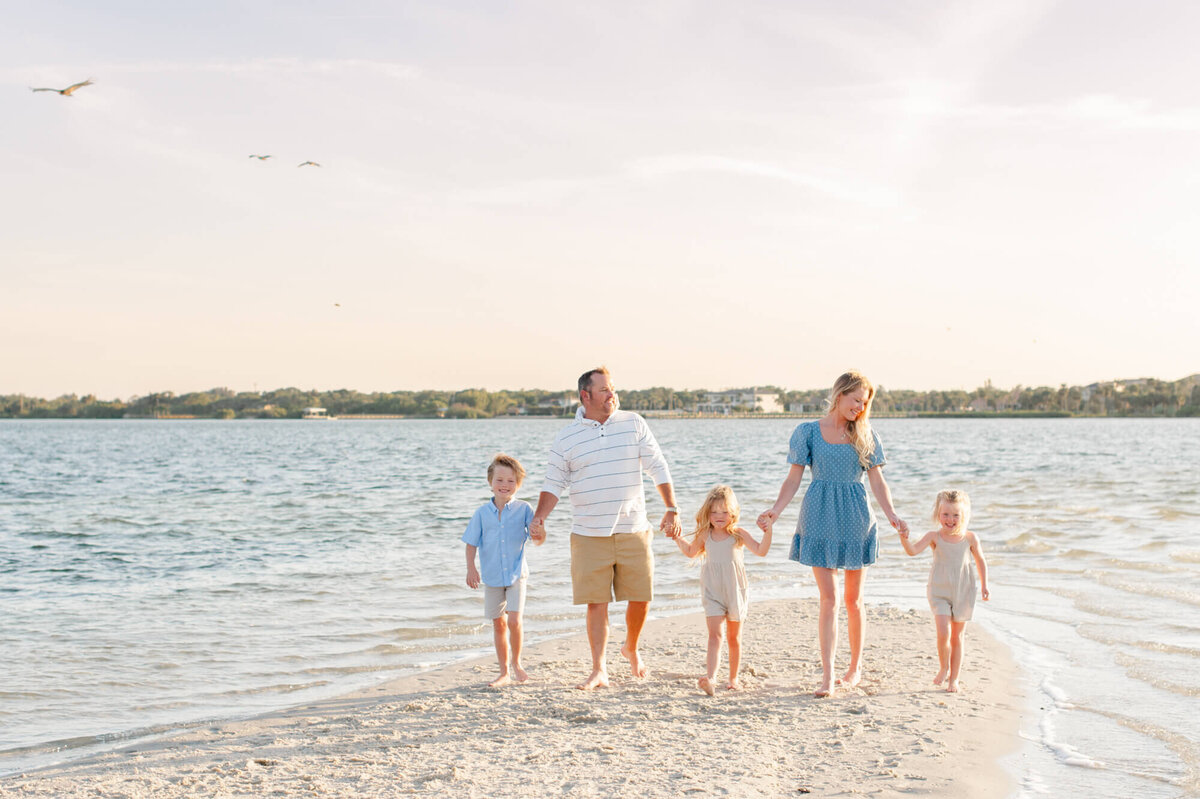 Family holding hands and walking on an island at sunset during family photos