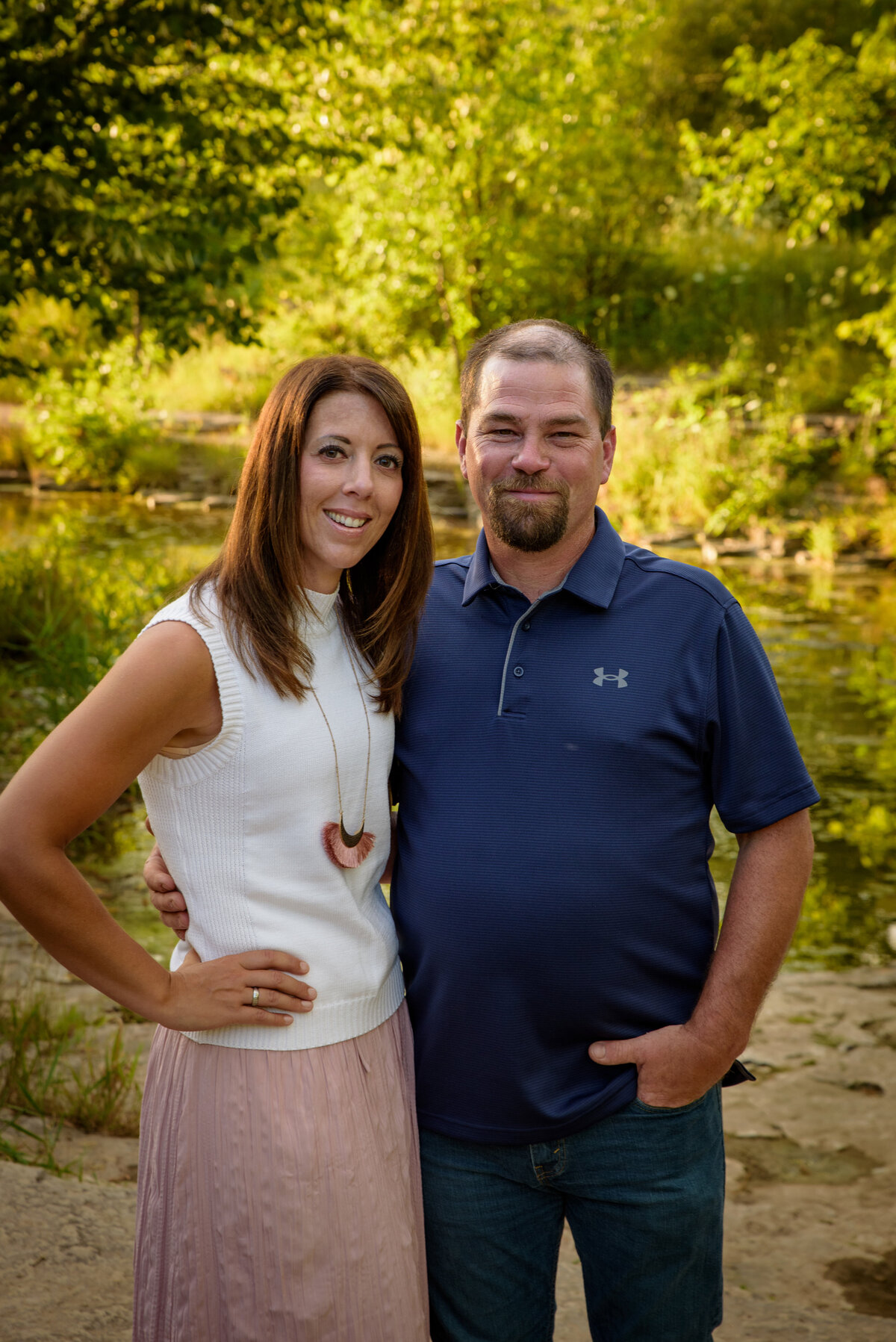 Portrait of a mom and dad standing with their arms around each other near the creek at Fonferek Glen County Park near Green Bay, Wisconsin