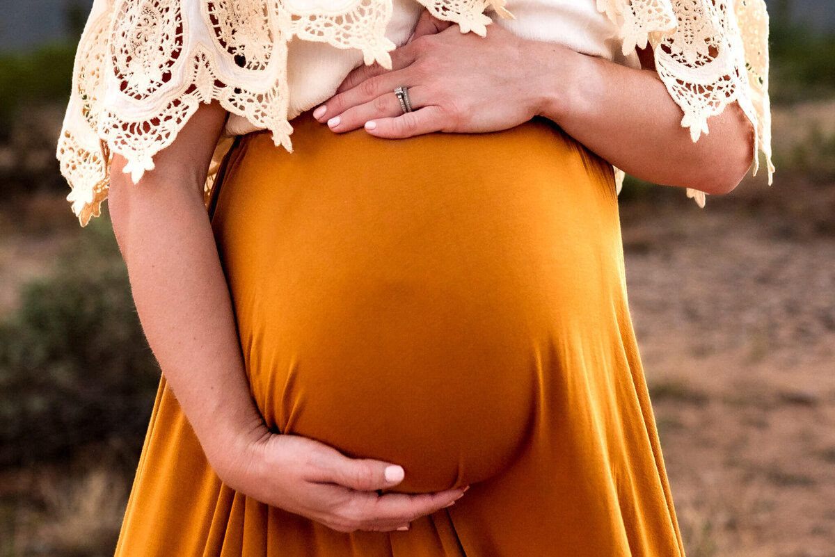 mom cradling maternity bump for close up photo taken by Cactus & Pine Photogrpahy