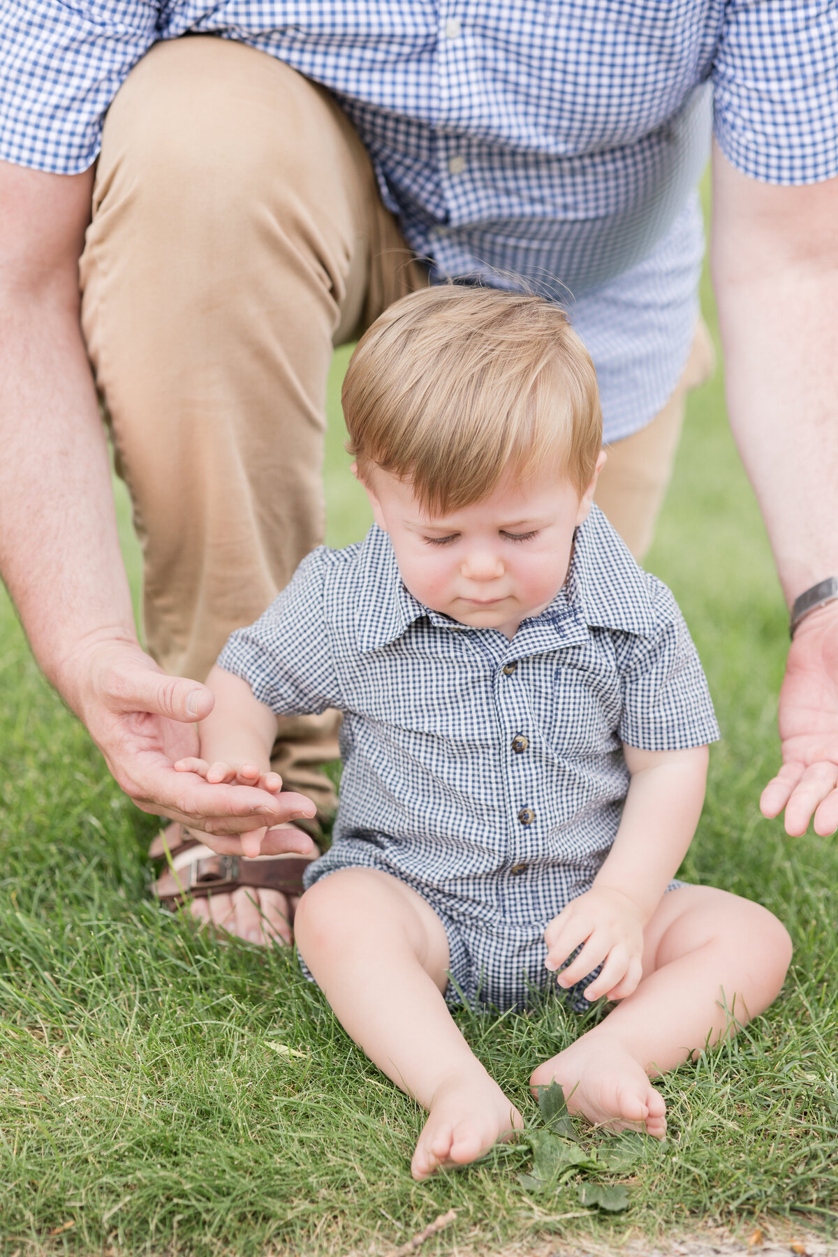 A dad crouches behind his seated baby