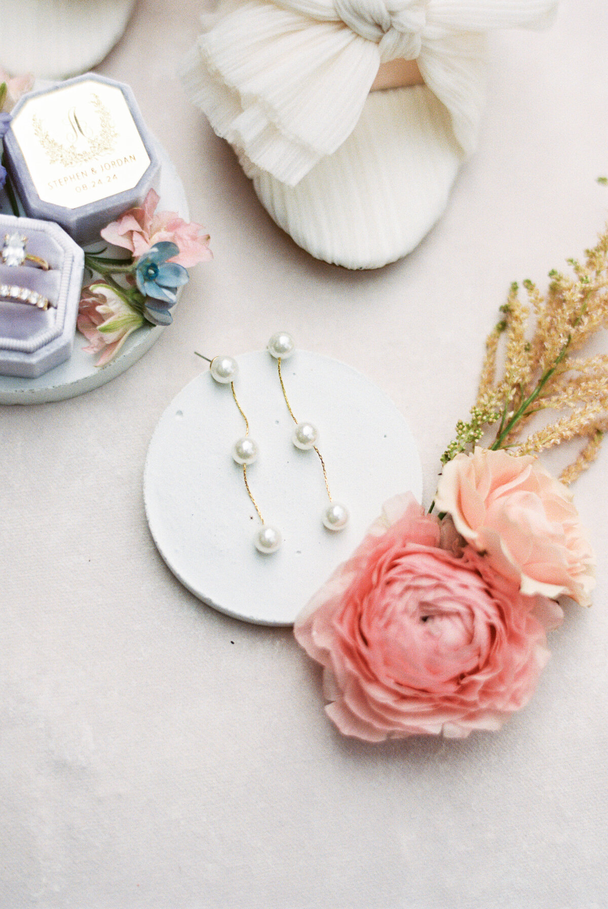 Bridal flatlay with pearl earrings, heirloom rings, ivory shoes, and pink garden florals at Gervasi Vineyard wedding