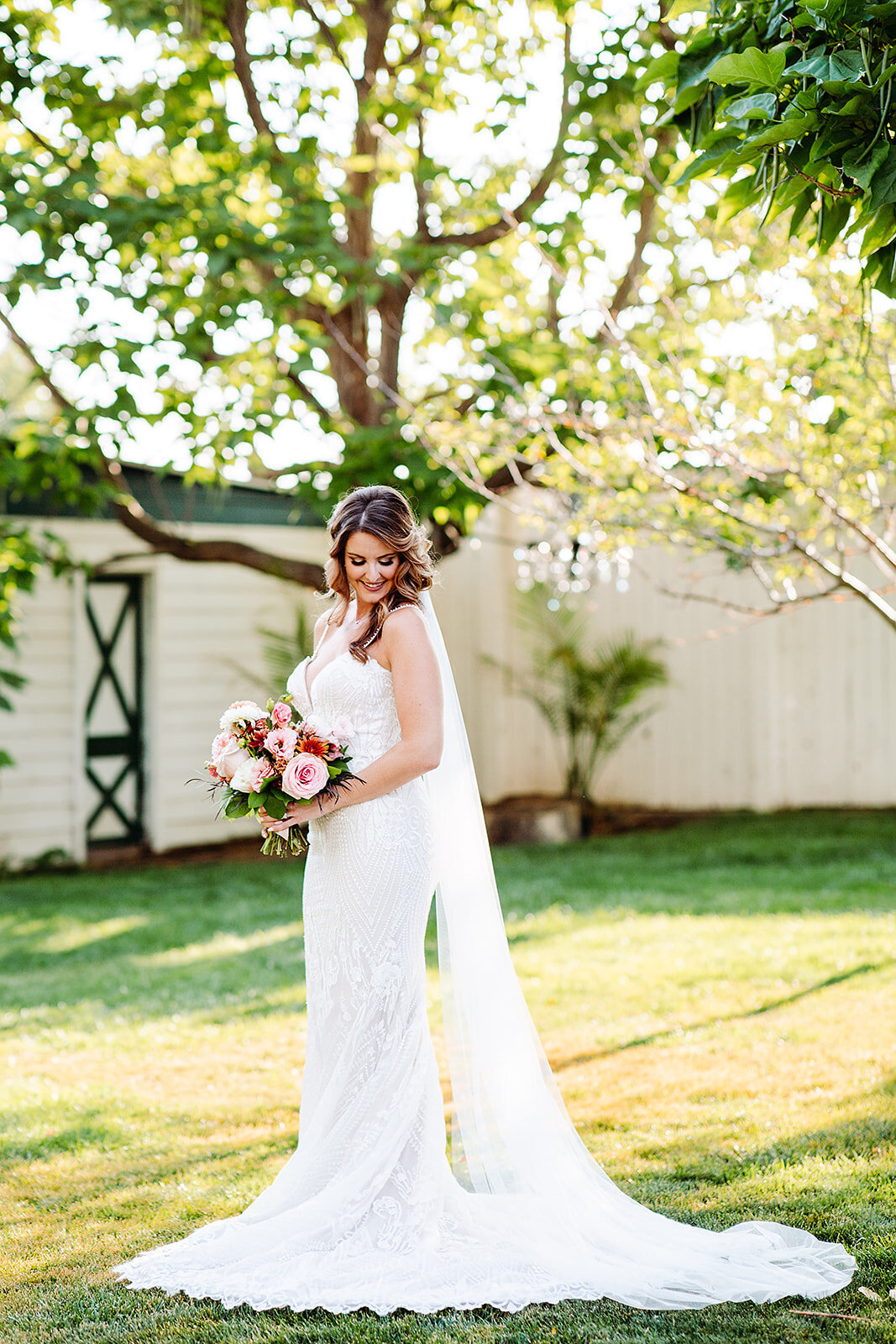 Bride poses before her wedding ceremony  at Lionsgate in Colorado with a pink orange and peach bouquet.