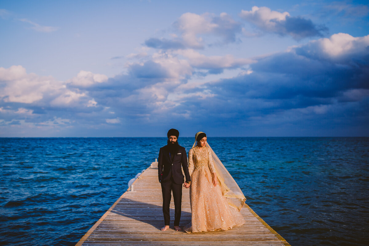 A sikh couple standing at the pier at sunset in mexico at moon palace cancun