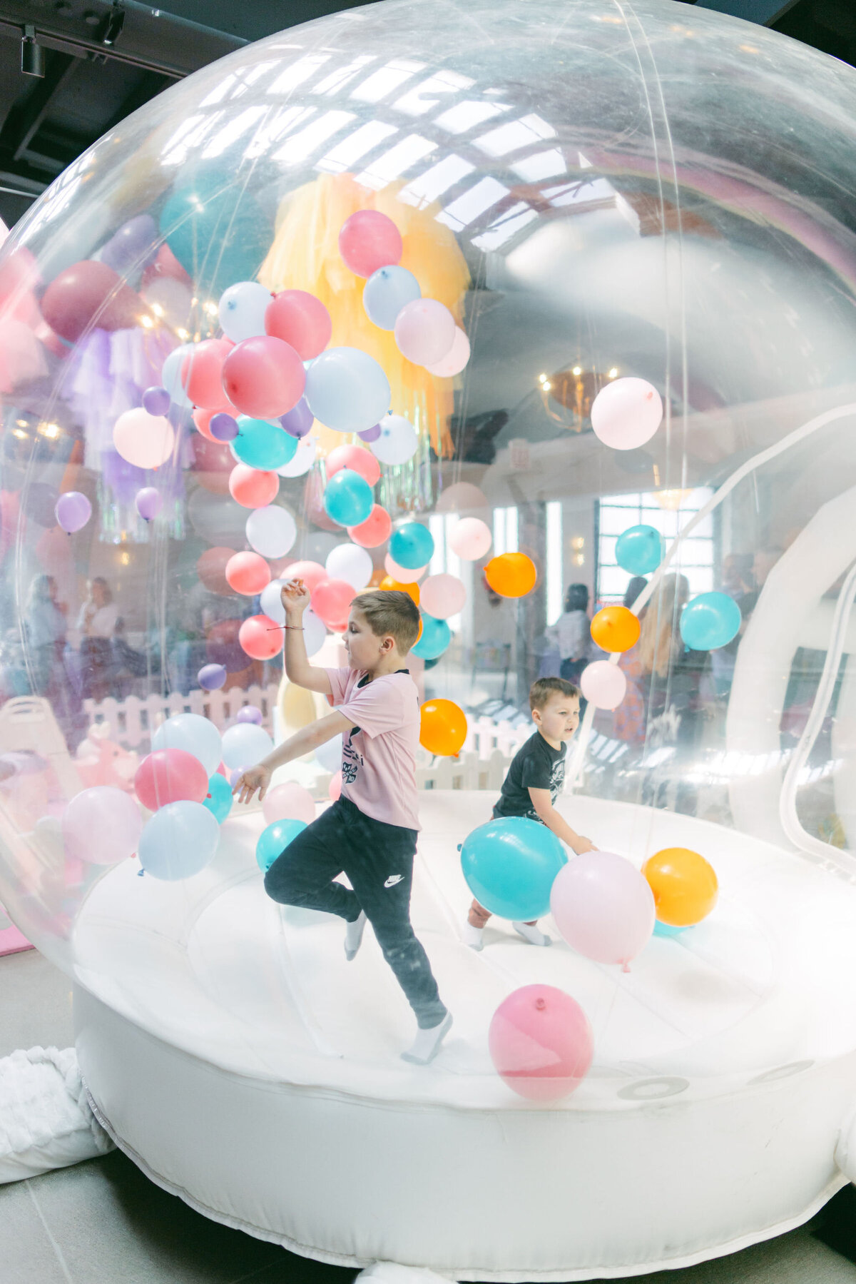 Colorful bounce house at a children’s birthday party venue, surrounded by vibrant balloons, playful decorations, and festive table settings, creating a fun and lively atmosphere